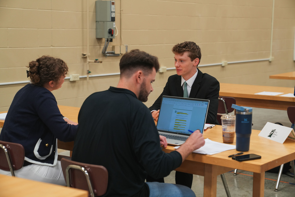 Academy of Finance Student in a suit and tie sits in a confident posture across the table from two First Bank & Trust representatives during a mock interview at the CTE Academy. (