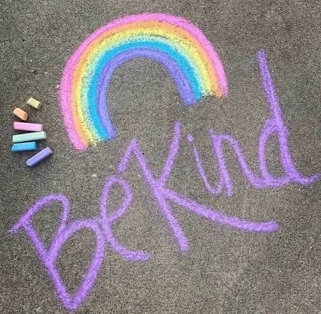 "be kind” written in chalk with a rainbow  