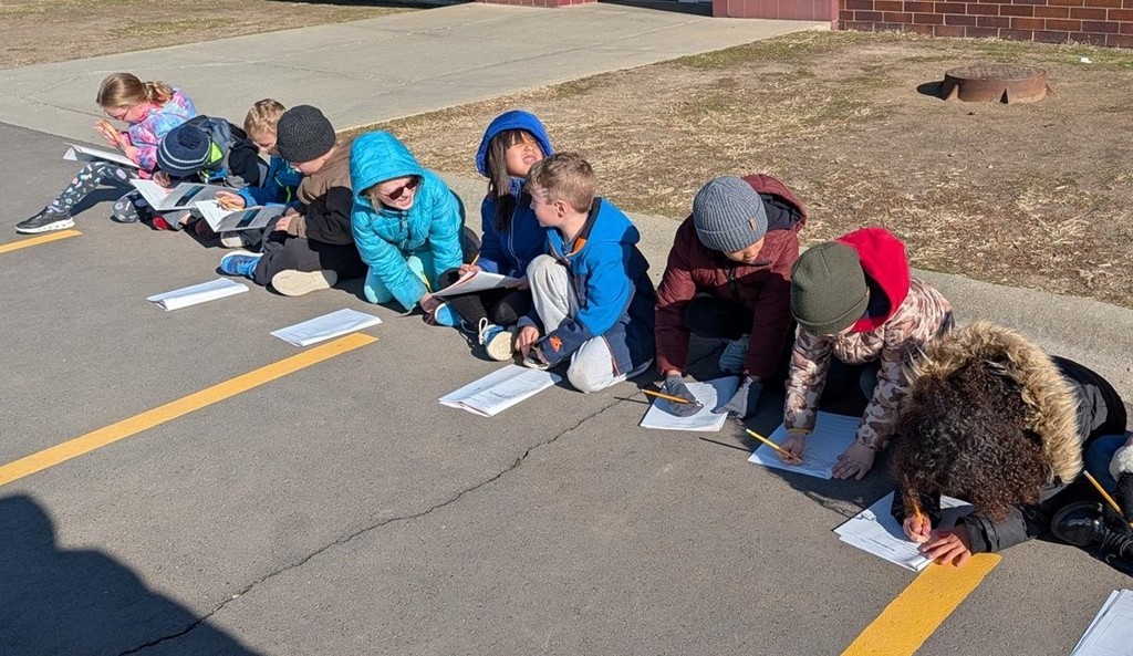 Students looking at the sky and drawing. 
