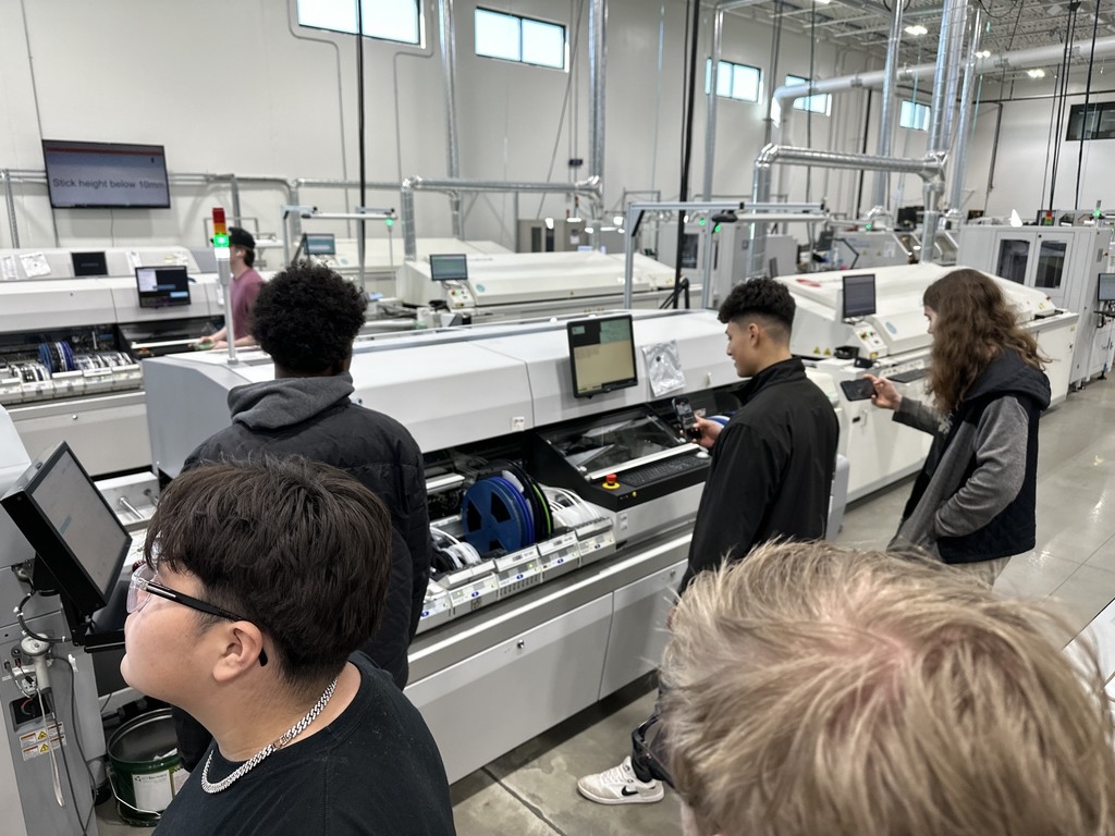 Students looking at the machinery for building vehicle dashboards