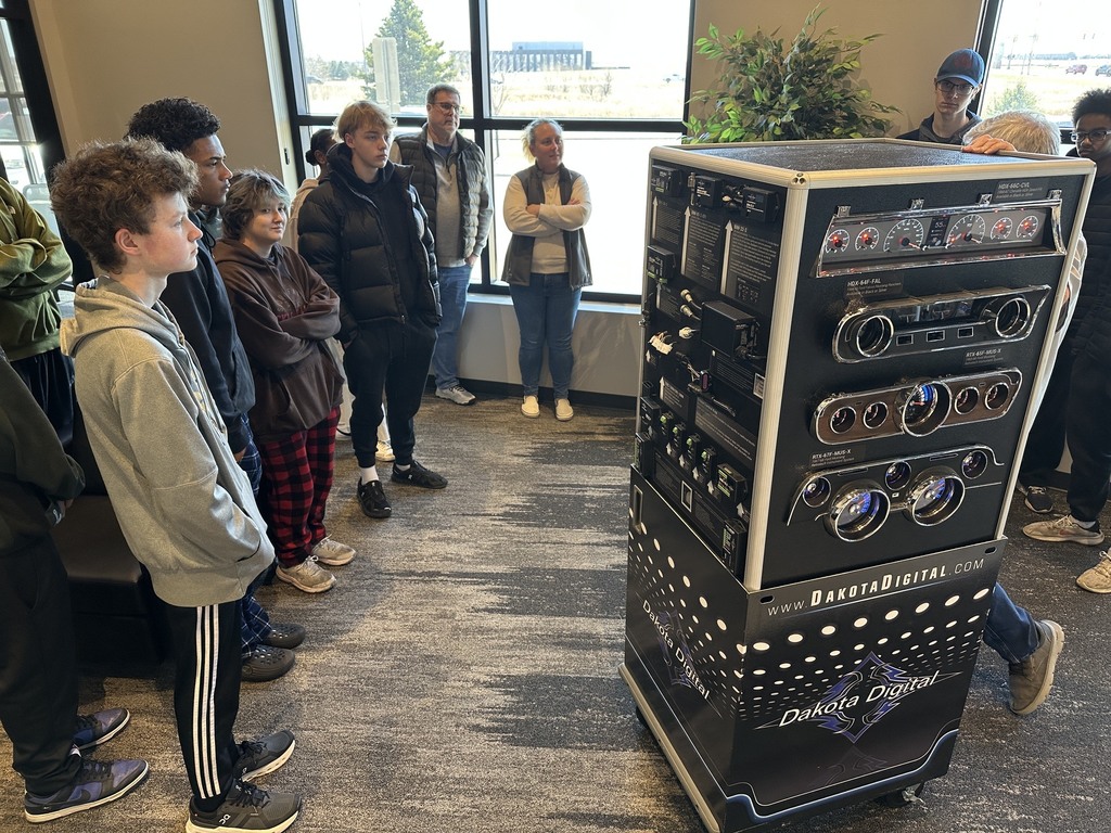 Students looking at floor models of dashboard electronics 