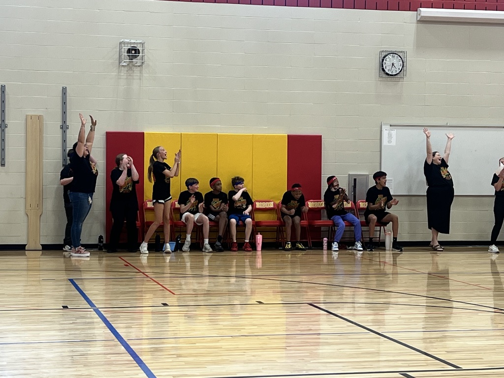 Members of the Ben Reifel Unity Team sit on the sidelines along with their coach, another BRMS staff member, cheering on their team as they run down the basketball court.