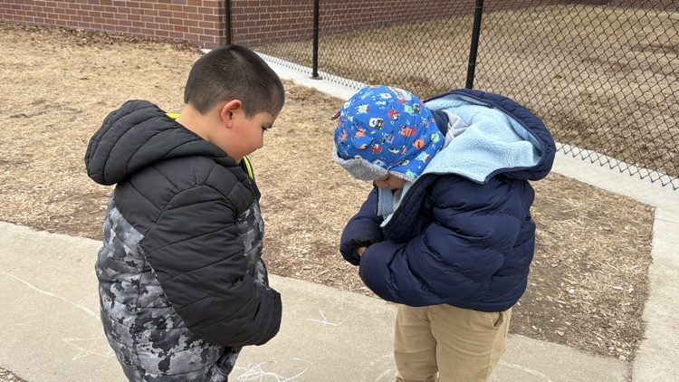 a student helping another student with zipping their coat