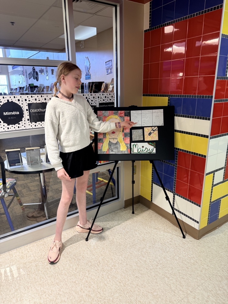 student delivering a monologue next to an easel of art 