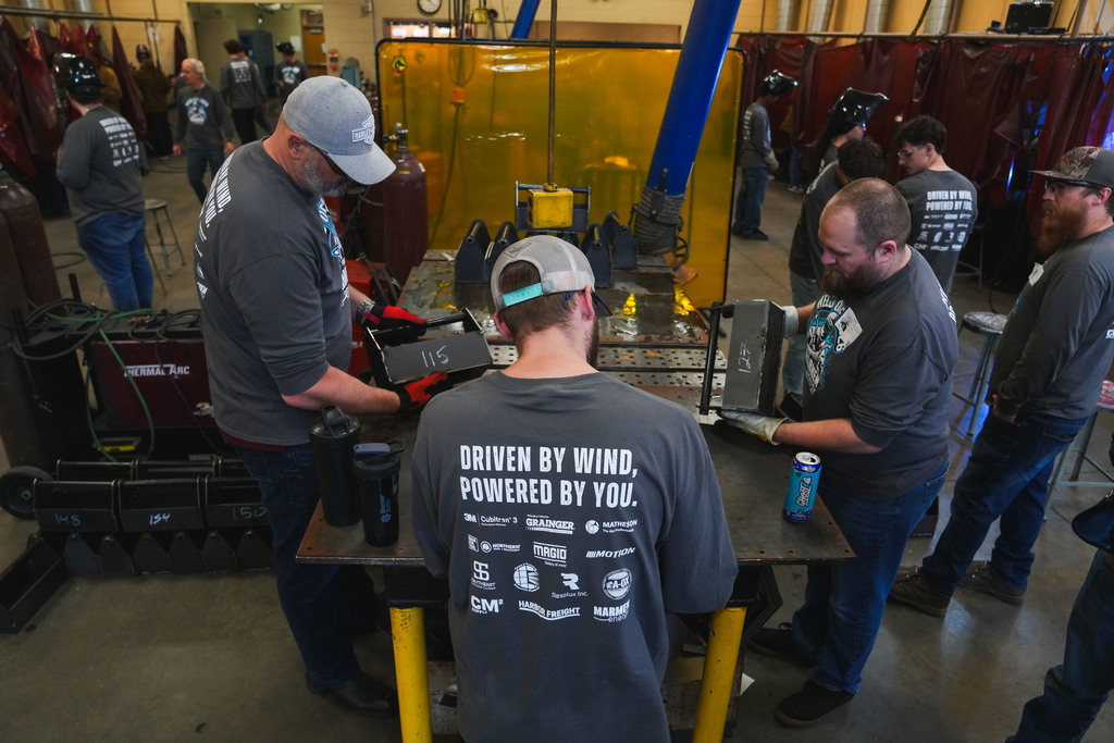 3 mend judge welded tool boxes while 2 other men look over their shoulders