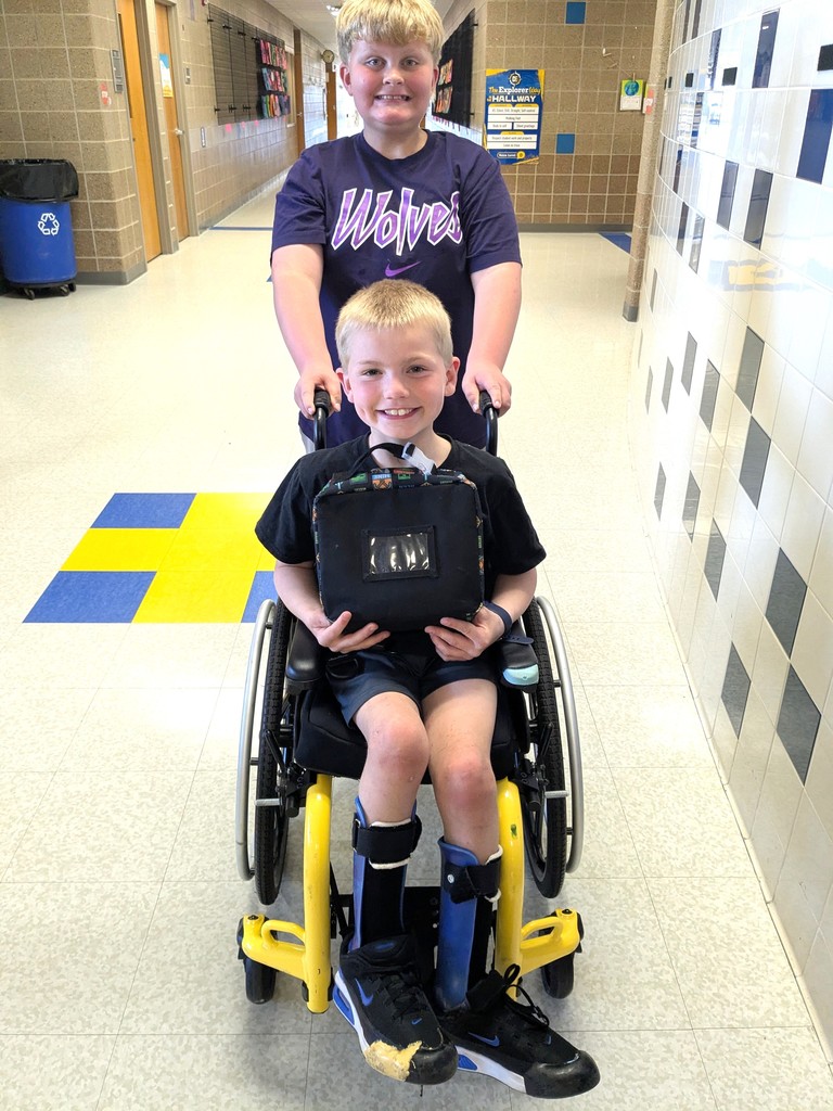 Two students in a hallway smiling. 
