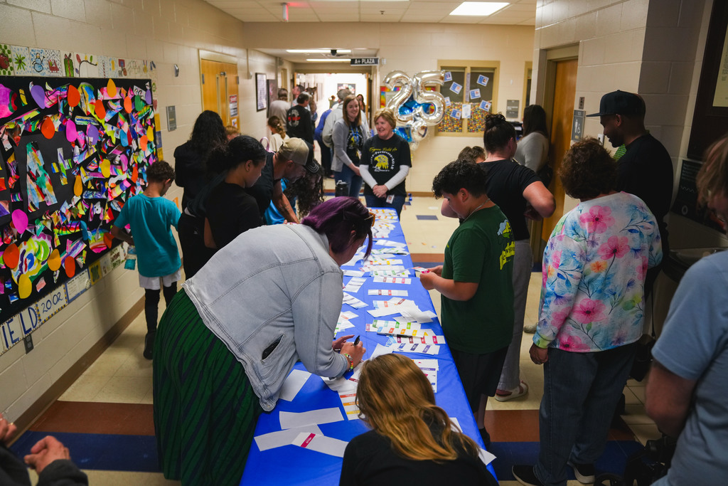 Parents and students fill out name cards at the entrance to a Eugene Field A+ Elementary