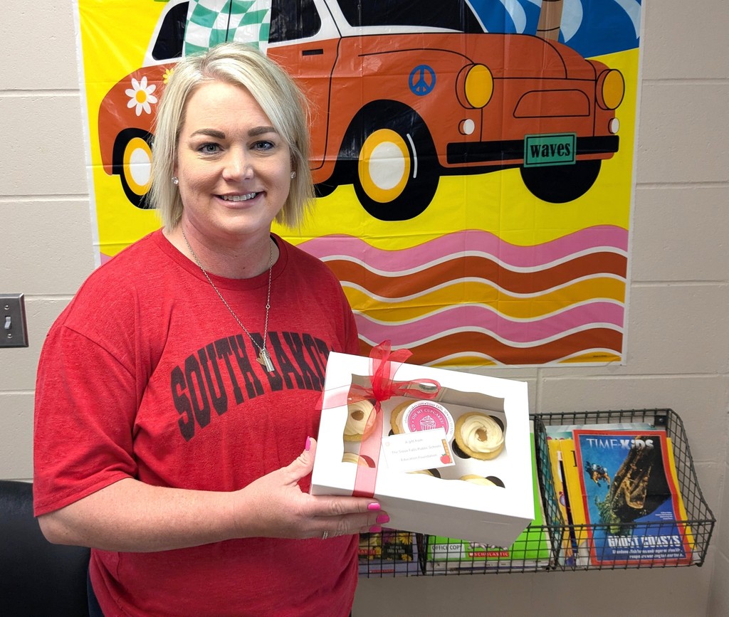 Teacher holding cupcakes.