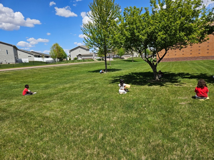students sitting in the grass reading