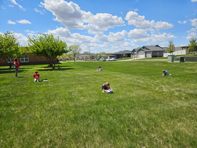 students sitting in the grass reading 
