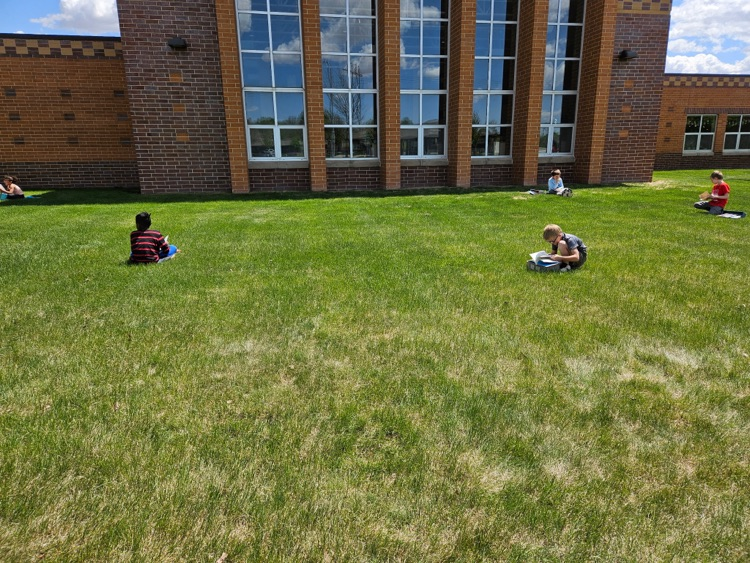 students sitting in the grass reading 