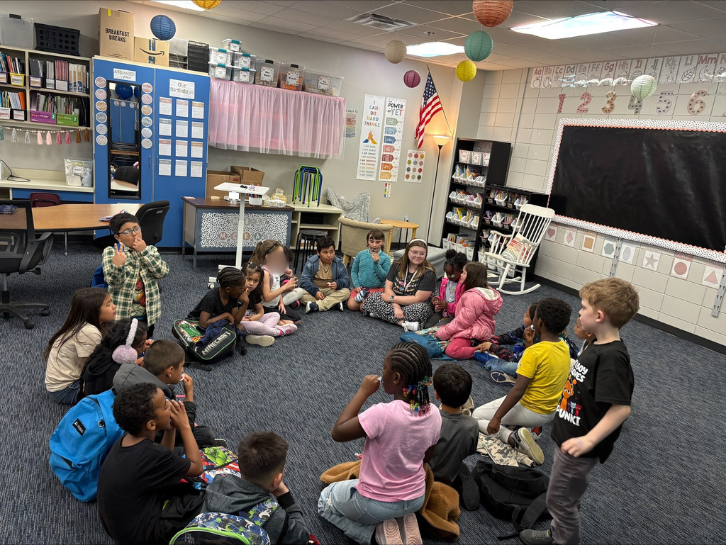 students sitting in a circle on the classroom floor with their teacher