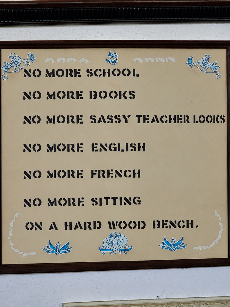 a sign reading: no more school no more books no more sassy teacher looks no more english no more french no more stiing on a hard wood bench