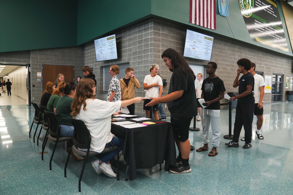 Jefferson High School students stand in a line in the commons area while waiting to receive back-to-school information from JHS teachers who sit behind a table at Cavalier Day on Friday, August 14, 2026. 