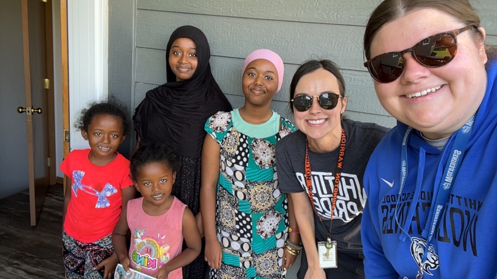 Whittier Middle School teachers stand smiling next to incoming WMS students and their younger siblings. 