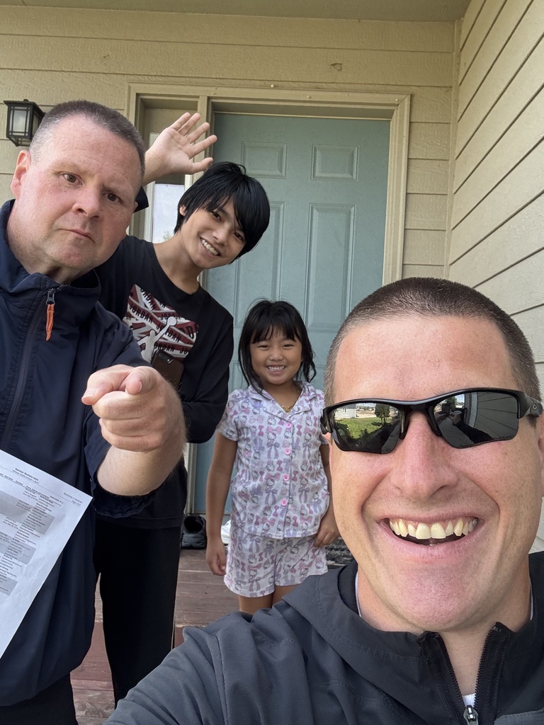 Two Whittier Middle School staff members pose in a smiley and goofy manner next to two smiling children. 