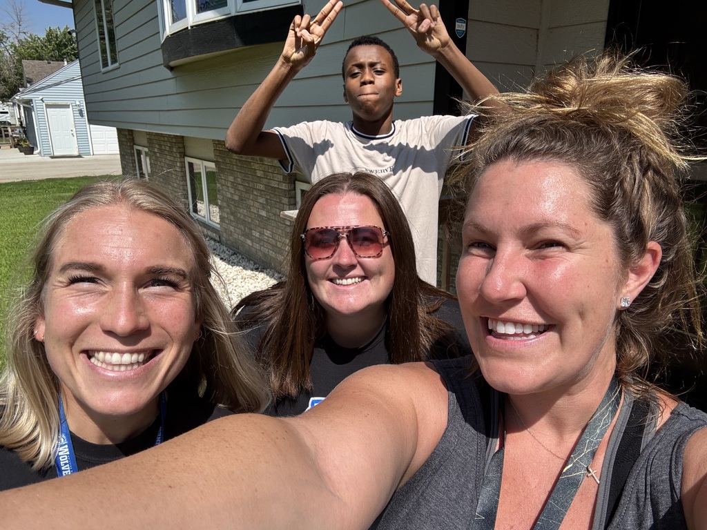 An incoming Whittier MIddle School student gives two thumbs up behind three Whittier MIddle School staff members who smile at the camera. 