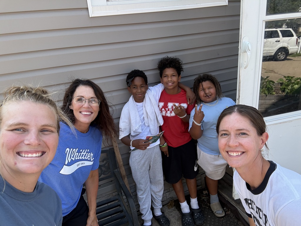 Whittier Middle School students stand outside a house excitedly alongside three Whittier Middle School staff members. 