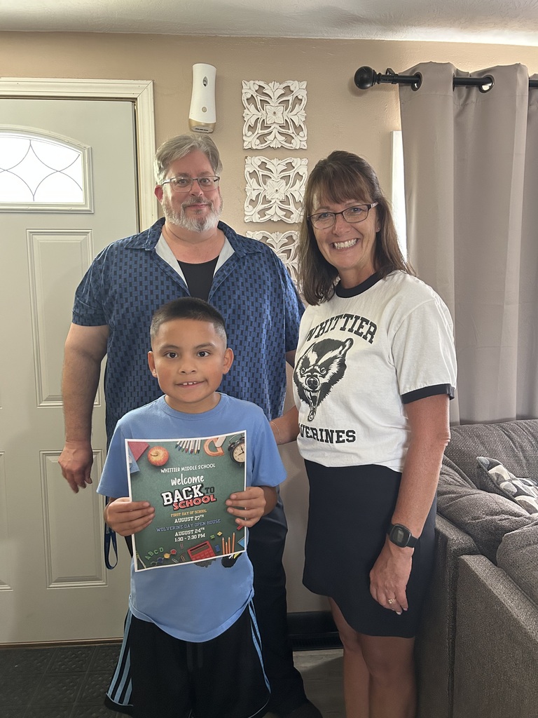 Two Whittier Middle Schools staff members stand smiling next to an incoming student who is holding a back to school sign.