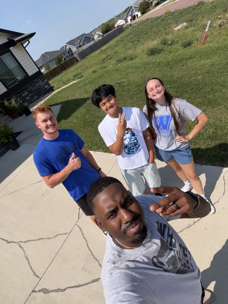 Whittier Middle School teachers stand next to an incoming student outside on a bright summer day, all with excited smiles on their faces giving a thumbs up.
