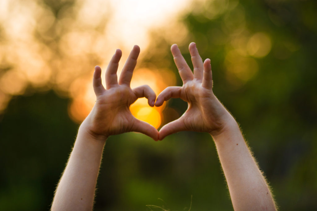 Child making heart symbol with hands.