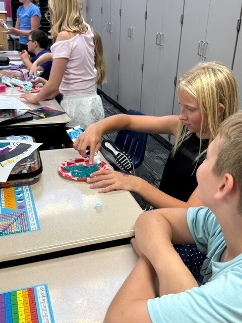 Students putting toothpaste on a plate. 
