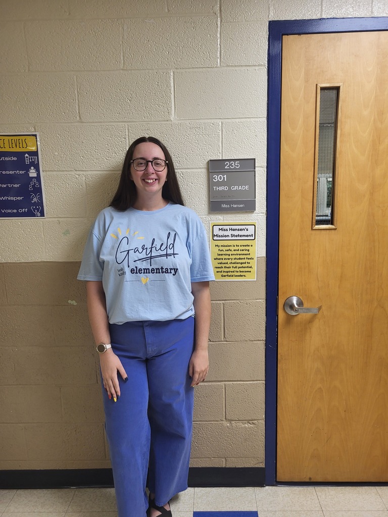 Miss Hansen standing outside her classroom door.