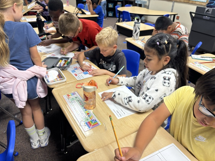 students sitting at their desk and writing their hero letters