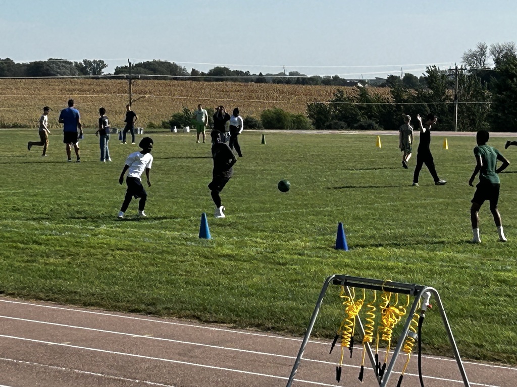 Group of students engaged in PE class out on the football field.