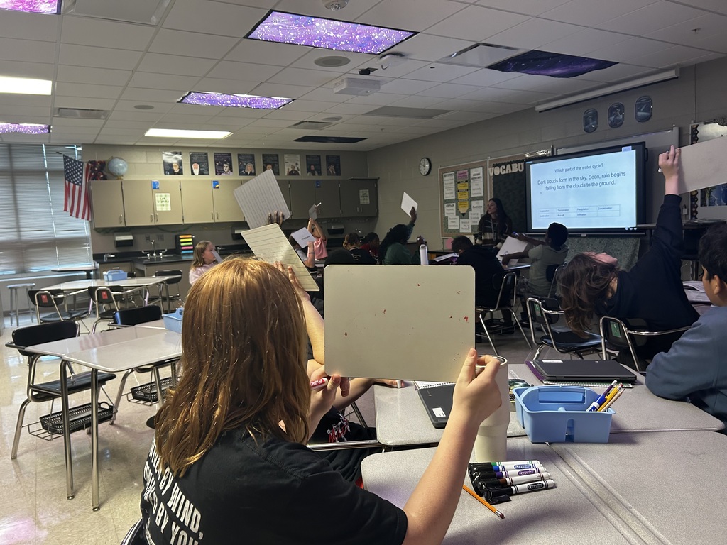 Students holding up whiteboards to answer questions for an informal check of learning.