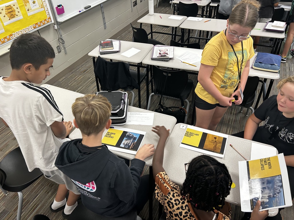 Four students sorting various pictures to put together a timeline of 9/11.