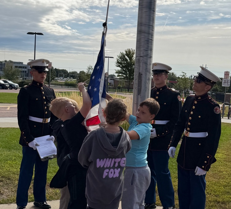 students hanging the flag with the help of cadets