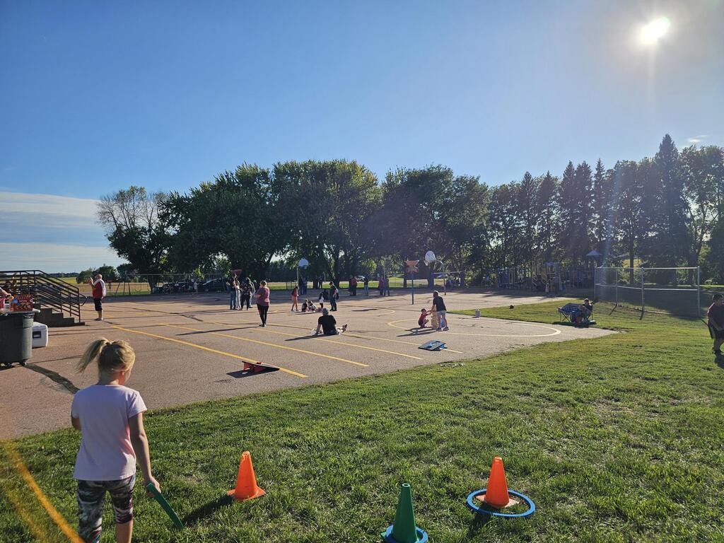 families scattered across the black top sitting, talking and playing games