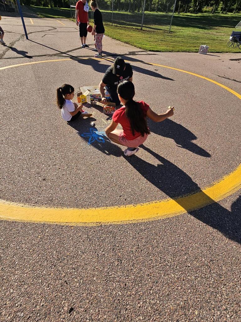 2 girls and a mom drawing with chalk outside