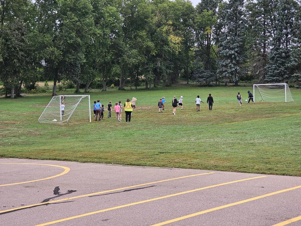 A large group of students playing soccer in the field