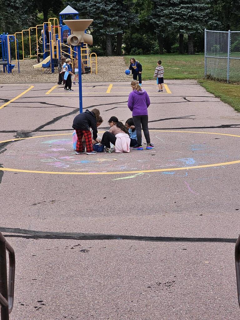 a group of students playing chalk and in the background playing 4-square