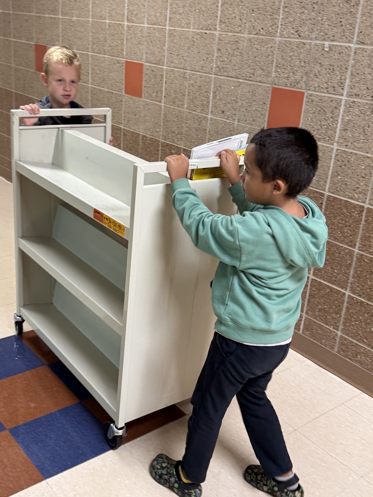 Students rolling library book cart down the hall