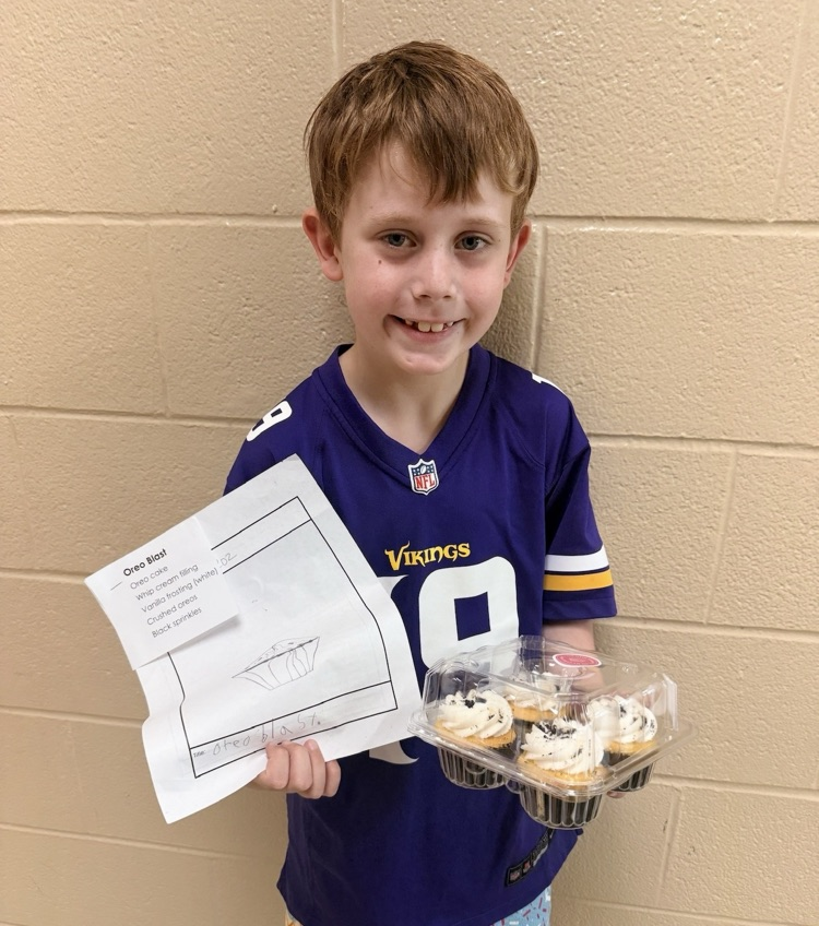 a student holding a paper and a package of cupcakes