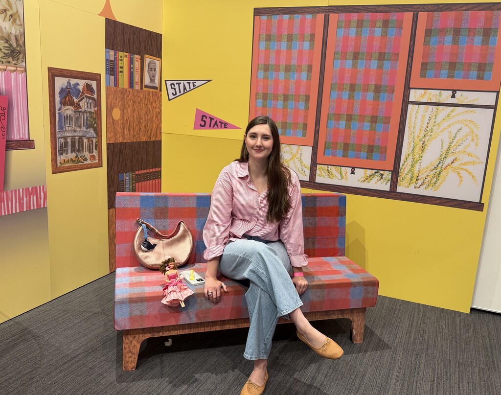 Miss Feterl at the Barbie exhibit sitting on a couch.