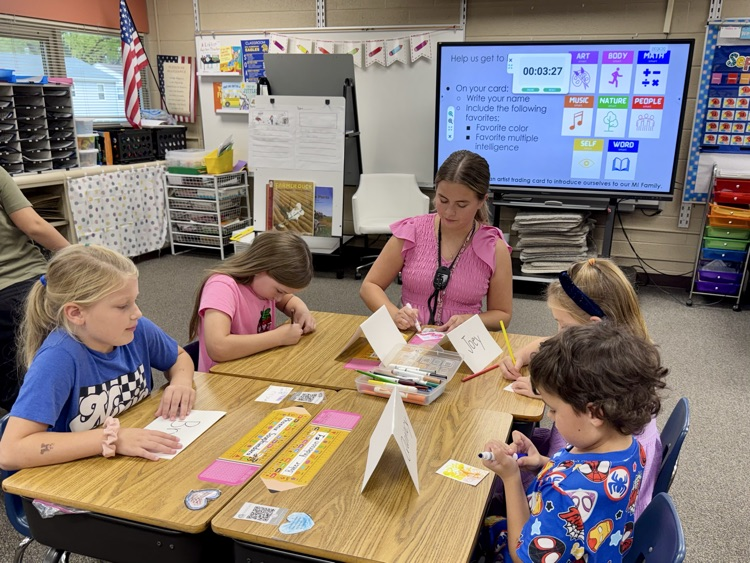 a group of students sitting with a teacher working on a project