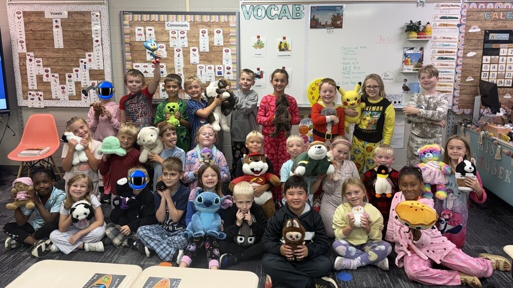 Students wearing pajamas and holding stuffed animals.