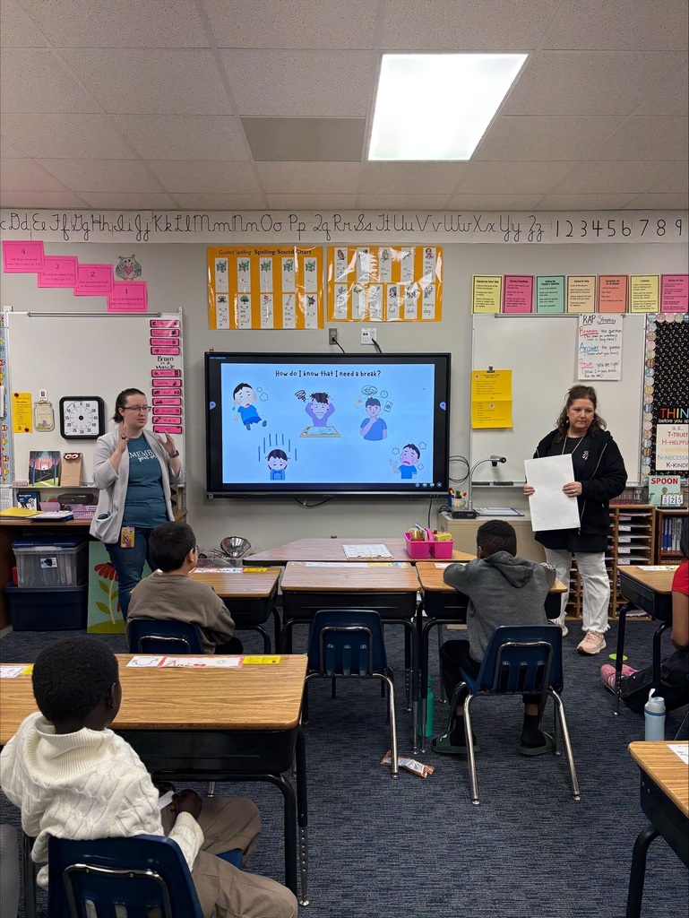 Front of a classroom with 2 teachers showing an image of a child taking deep breaths to calm down