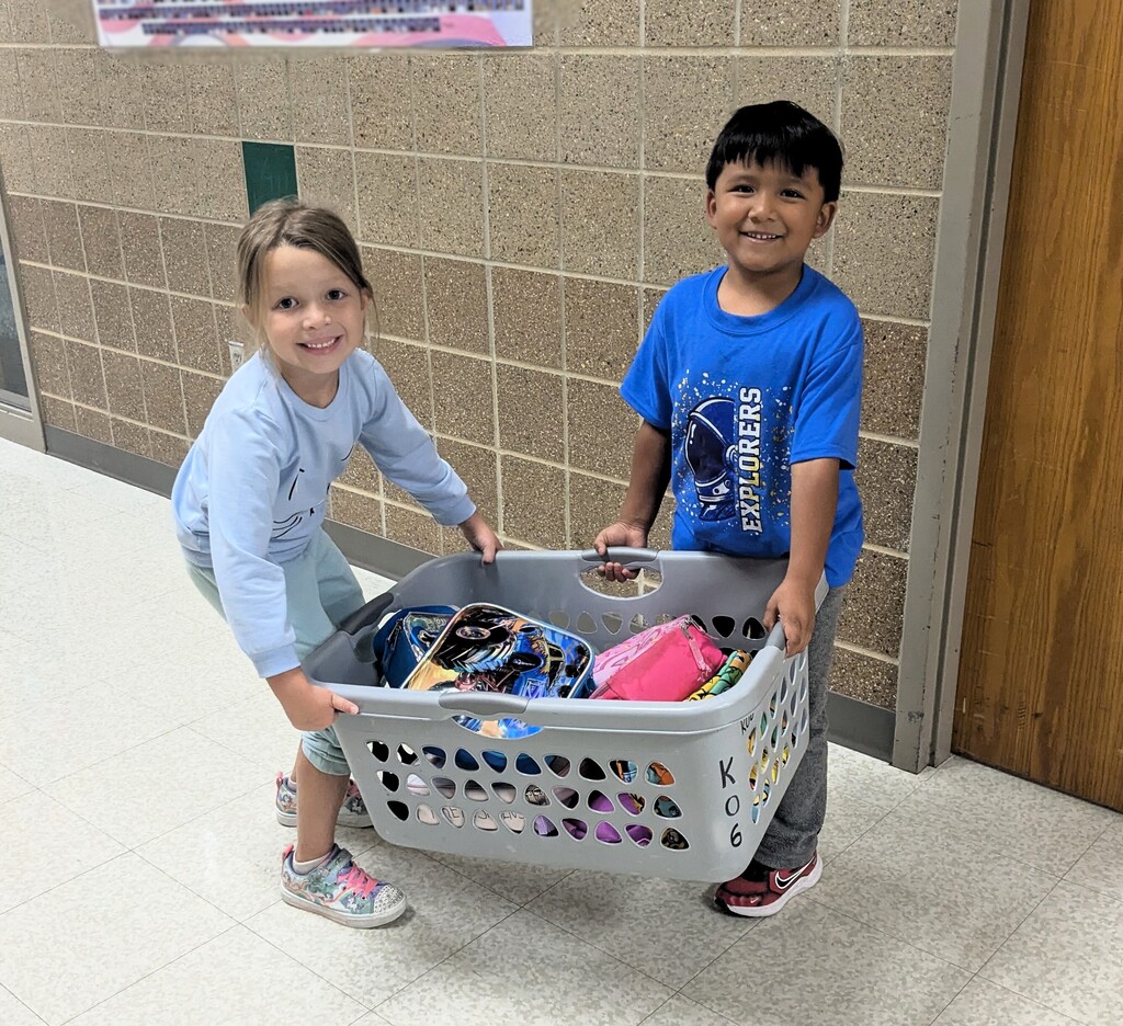 Two students carry laundry basket.
