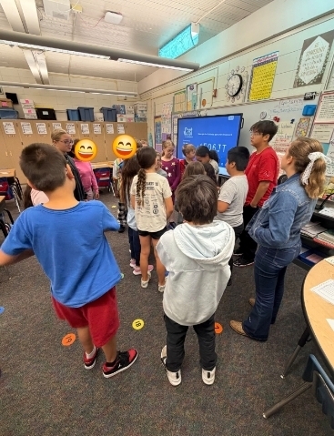 The students in 451 standing together in a group having a discussion