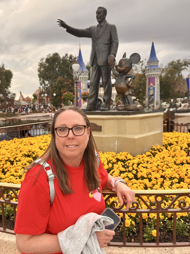 Mrs. Lamoreux sitting by a statue of Walt Disney.