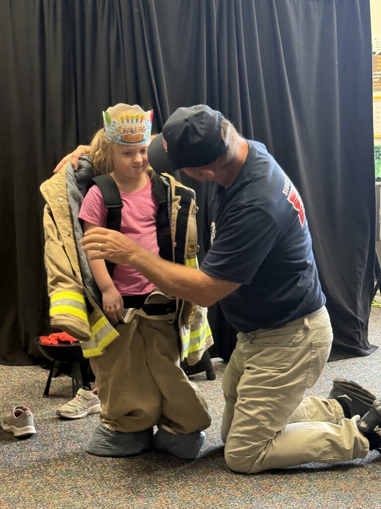 A girl putting on a fireman's outfit