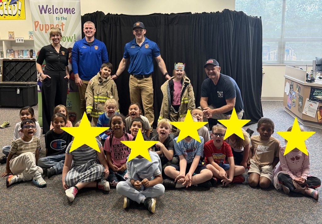kinder and 1st grade students posing for a phot with 4 firemen