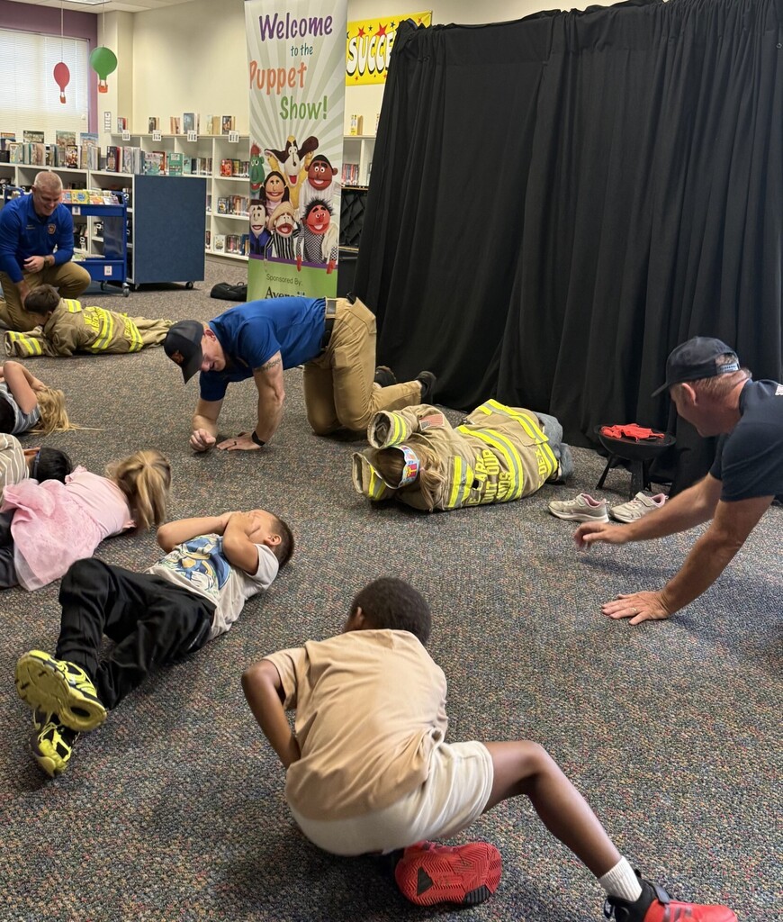 students and firemen on the ground, stop, drop and roll