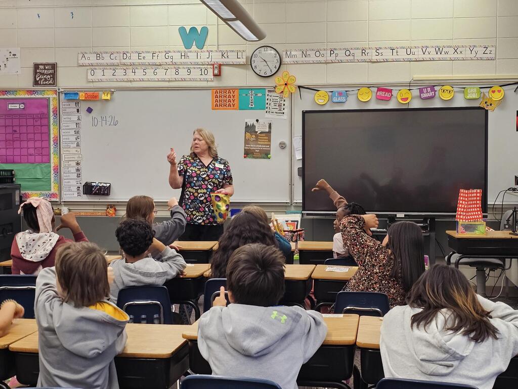 Students watching the adult do a magic trick.