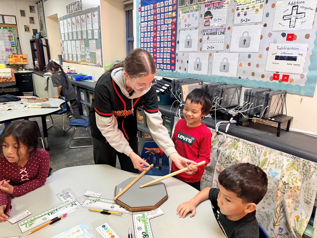 older student showing younger students how to drum